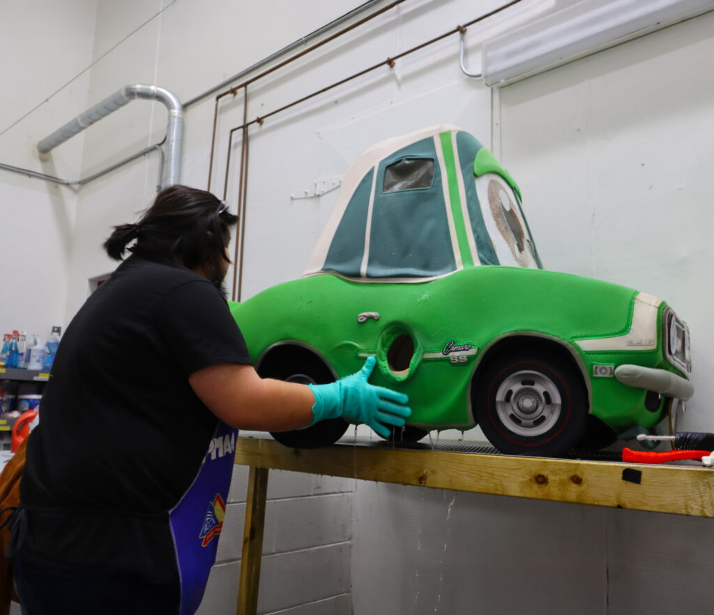 Mascot cleaner washing down a foam car mascot
