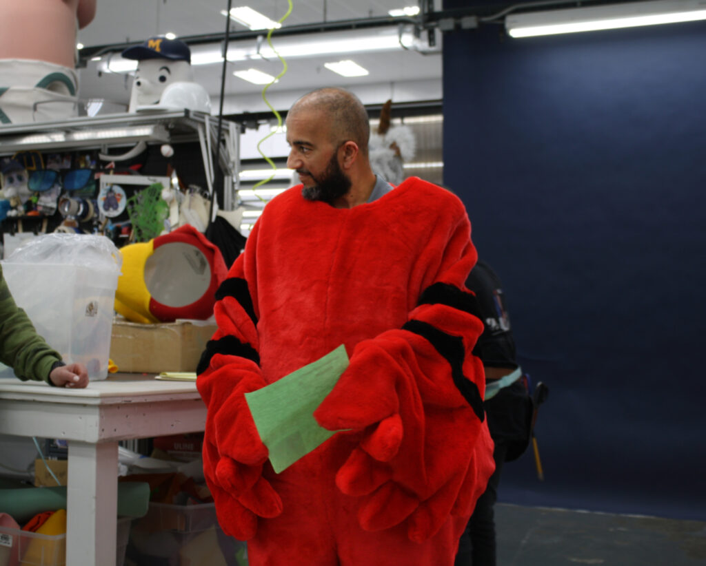 Olympus employee putting on a custom mascot costume.