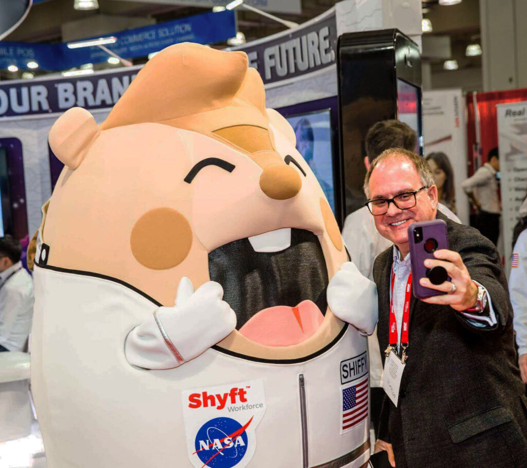 Shyft Technologies' Mascot, Shiffy, taking a selfie with a fan.