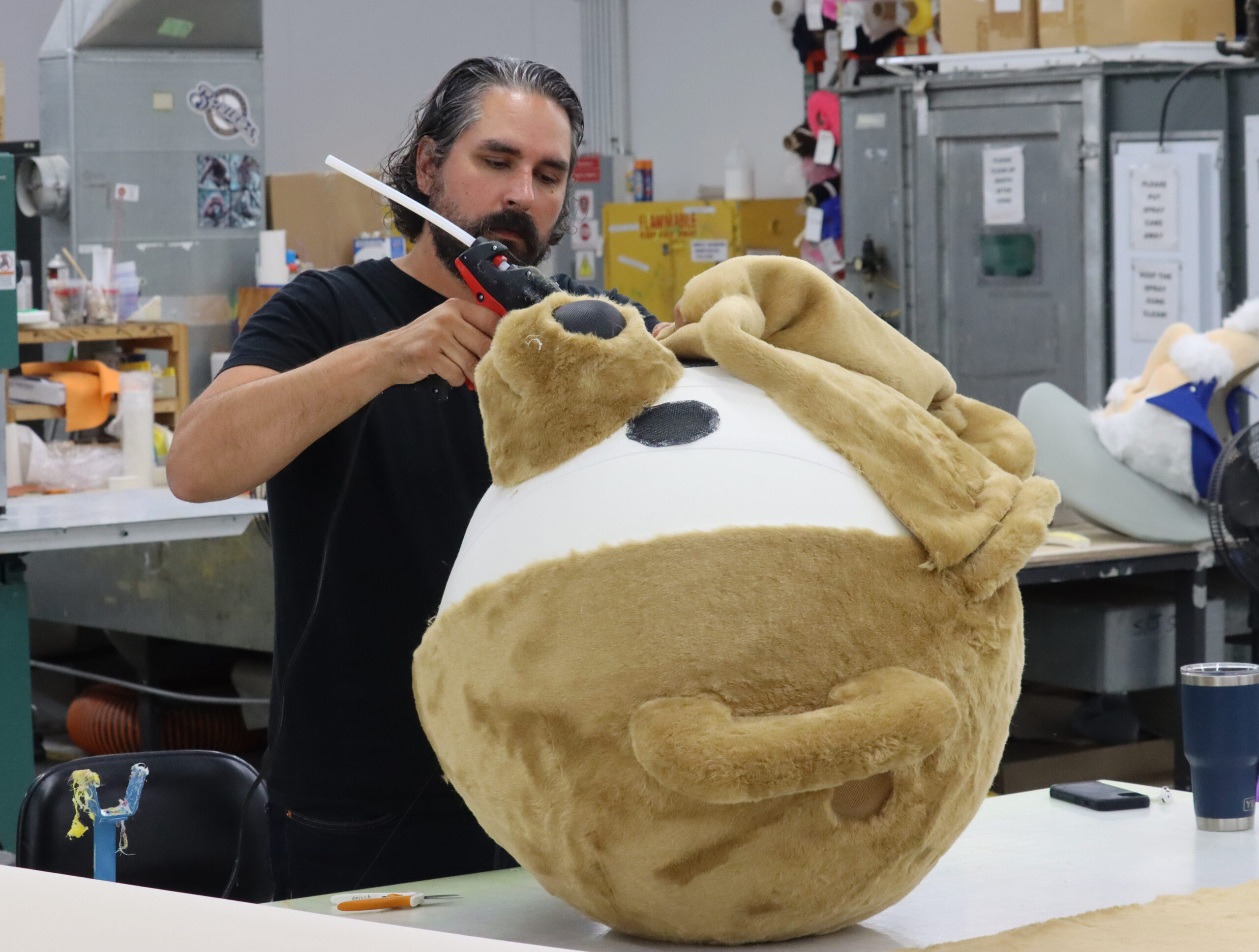 Mascot designer gluing on custom mascot fur onto a foam mascot head.