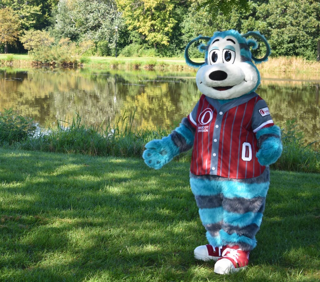 Oly Olympus Mascot outside near a lake.