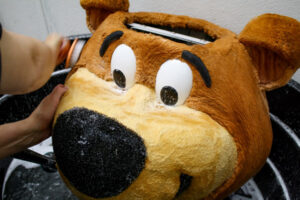 Yogi bear mascot head being hand washed with soap