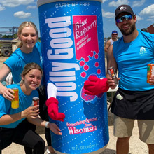 Dark blurred background photo of happy athletes with a beverage mascot