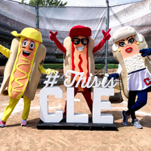Cleveland Indian's hot dog mascots pose around sign