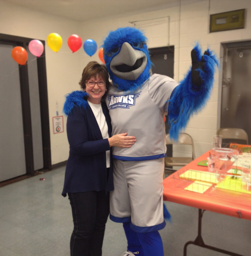 Hawk school Mascot taking a photo with faculty