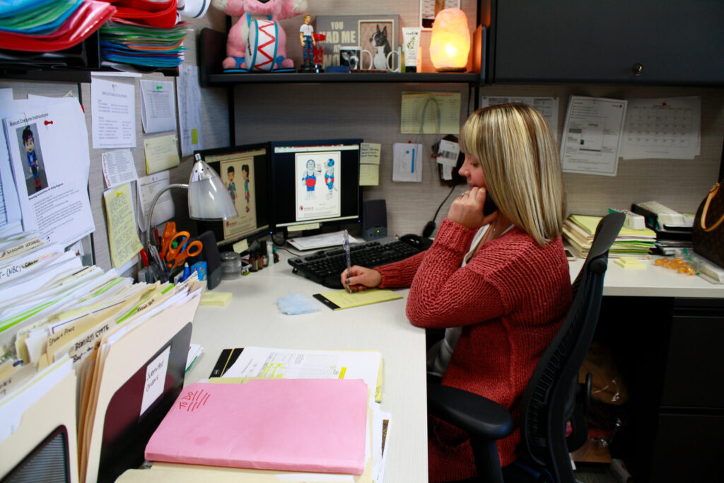 Olympus Mascot Sales member working at her desk helping a client.
