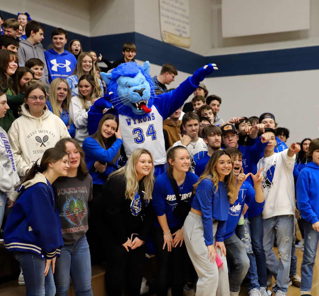 Wykon Mascot cheering on basketball team in student section.