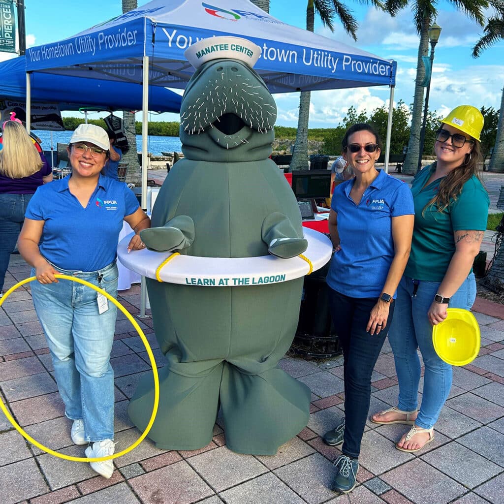 Moe the Manatee Mascot surrounded by representatives of the FPUA outdoors.