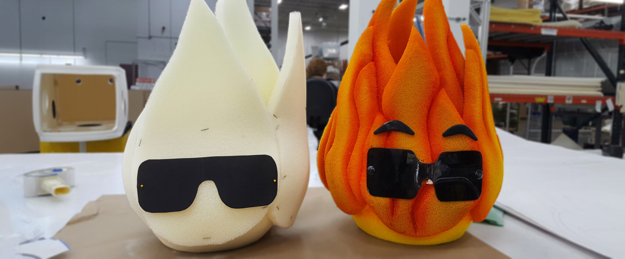 A work in progress foam mascot head in the shape of a flame next to the finished product of the foam mascot head.