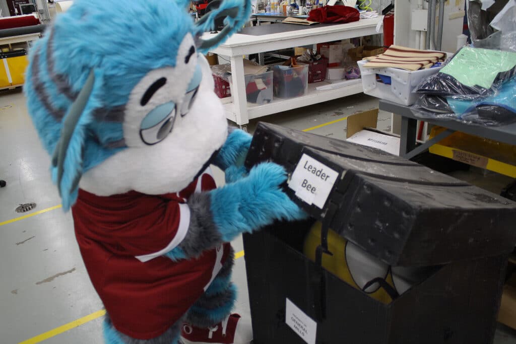 Ollie Olympus Mascot opening a storage container with a mascot in it.