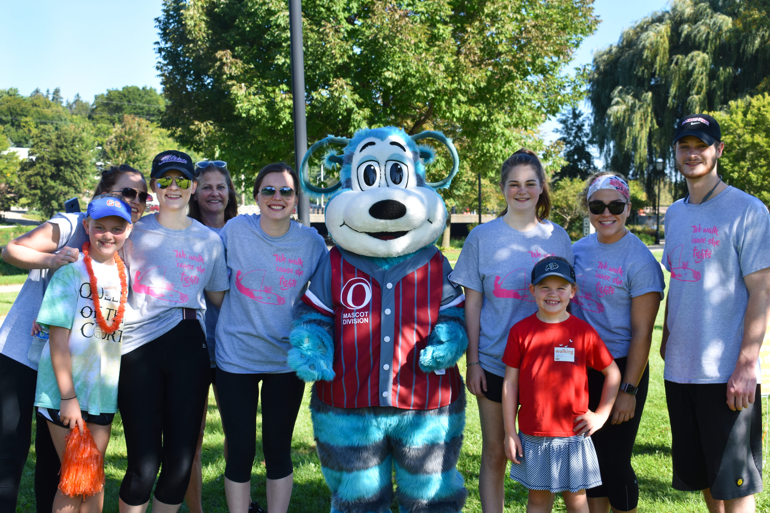 Oly Olympus posing with a group of people at a park.