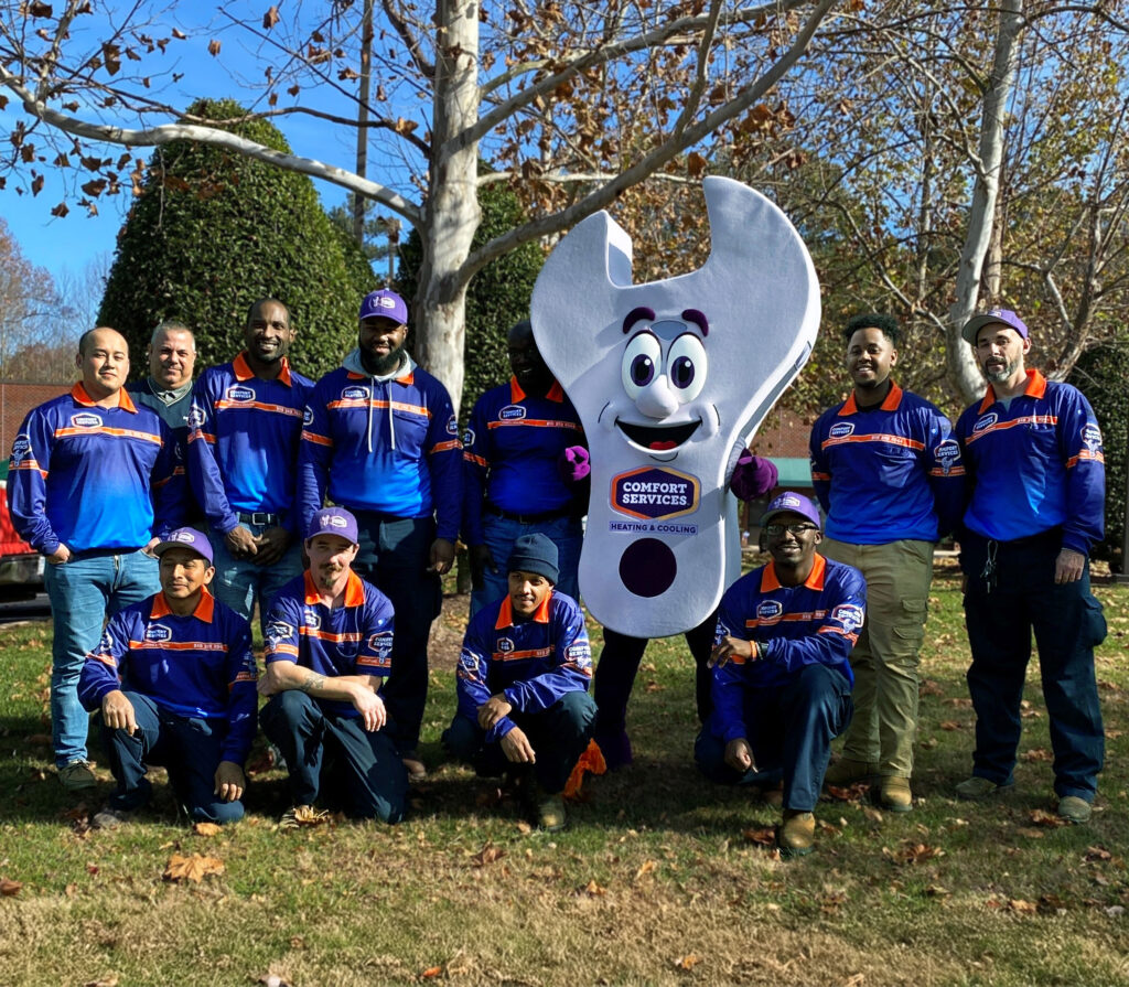 Comfort Services Wrench Mascot taking a photo with some company employees.