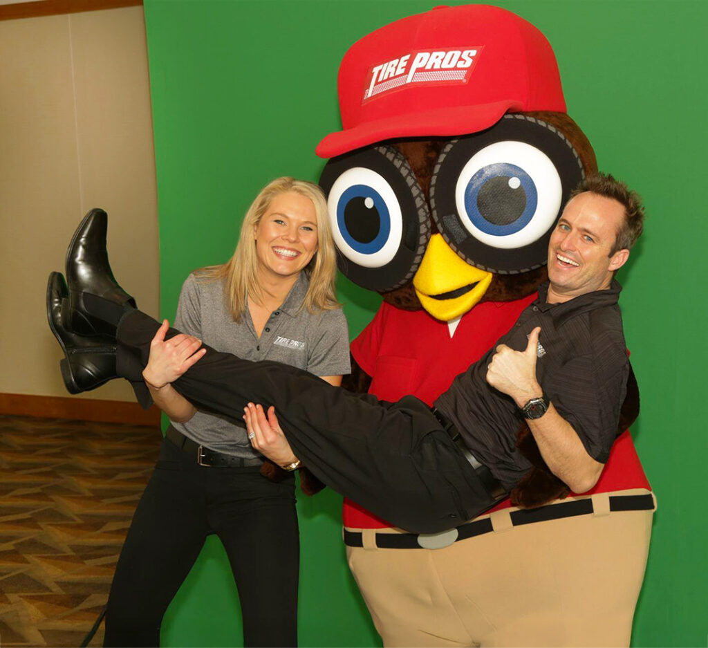 Olympus customers posing with their custom bird mascot from Tire Pros.