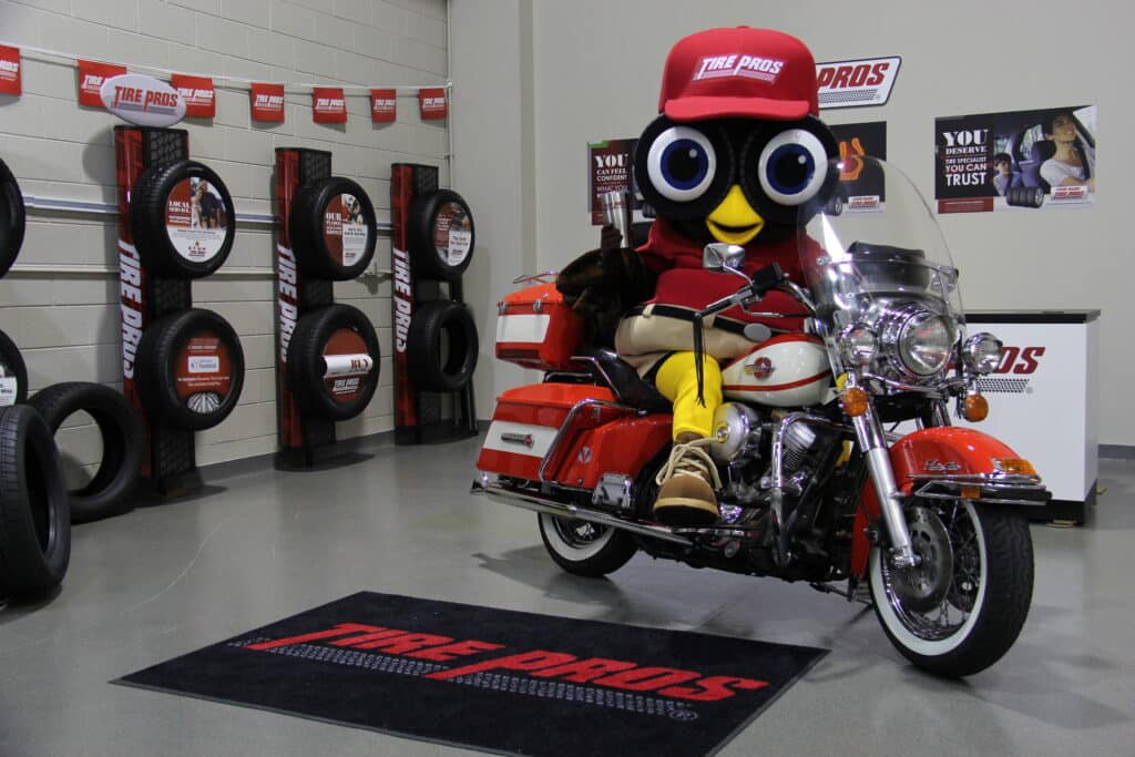 Hootie from TirePros posing on a motorcycle in a store.