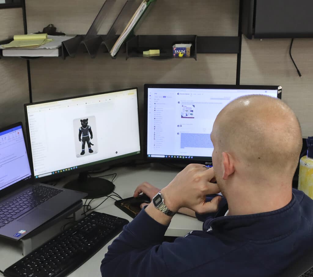 A man in an office prompting AI to give a custom panther mascot sketch.