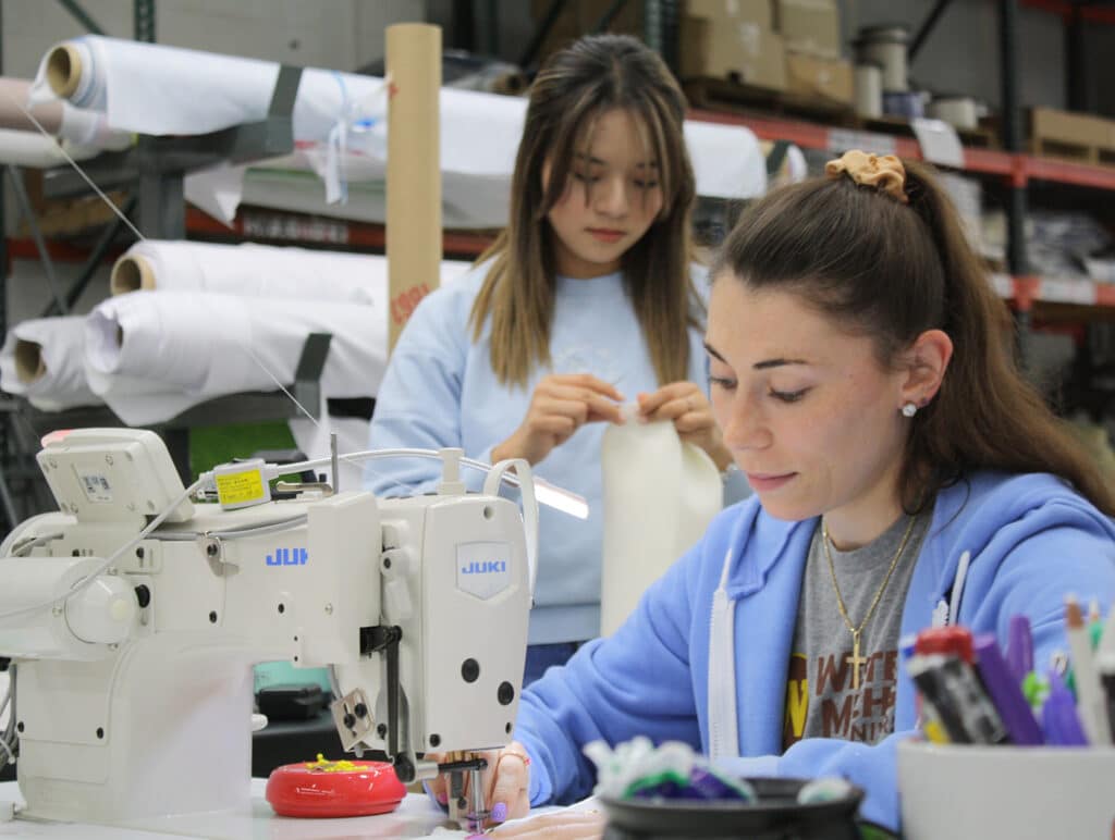 Two Olympus employees sewing mascot patterns.